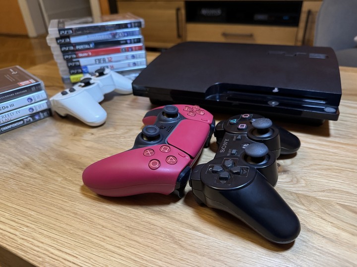 Kontrolery Sony znacznie się zmieniły pod względem rozmiarów. Po lewej malinowa wersja kontrolera do PS5, po prawej czarny pad z PS3. W tle biały kontroler do PS3. | Źródło: fotografia własna. - To nie była najlepsza premiera Sony. PlayStation 3 kończy 18 lat, ale konsola rozwinęła skrzydła dopiero po czasie - wiadomość - 2024-11-12